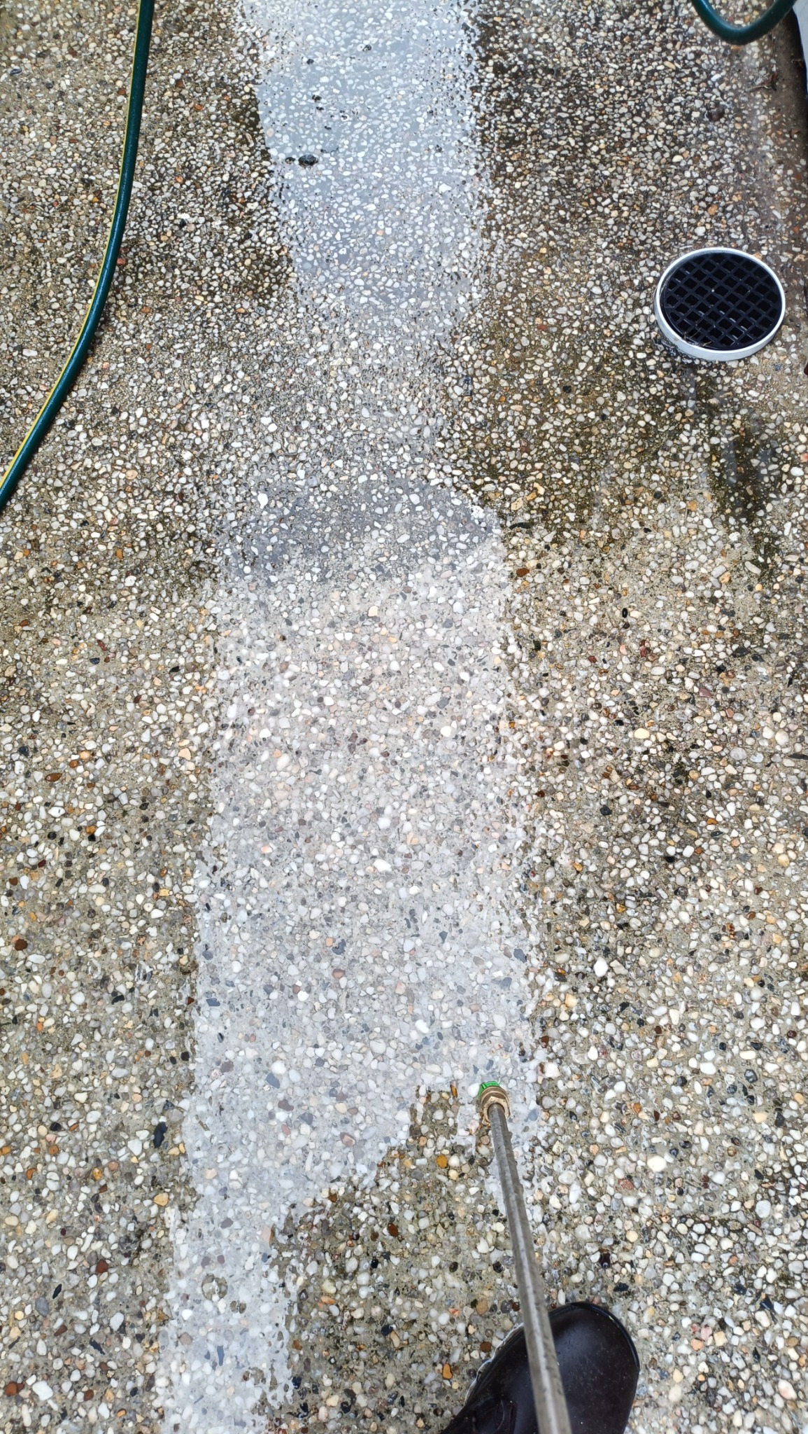 Pressure washing in progress showing the cleaned strip against the weathered surface